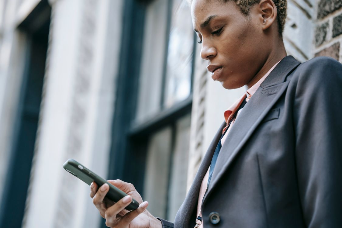 A professional using her smartphone outside a building